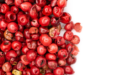 Lot of whole peruvian pink pepper on the left side flatlay isolated on white background