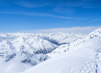 Winter landscape with snow covered mountain slopes and pistes with skiers enjoying spring sunny day...