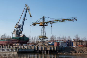 Fototapeta na wymiar Large spacious dry-cargo barge with cranes on the blue sky background