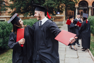 Happy students in graduation gowns on university campus ! Lifestyle! Education!