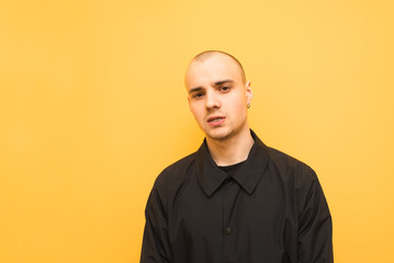 Obraz premium Portrait of a stylish boy in a black jacket is on a yellow background and looks at the camera. Authentic, stylish young man is isolated on a colored background. Copyspace