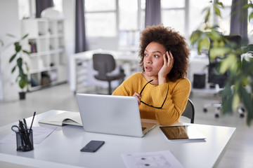 Cute mixed race businesswoman dressed  casual thinking how to solve a problem while sitting in...