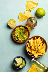 Nachos, guacamole and beer on blue background,