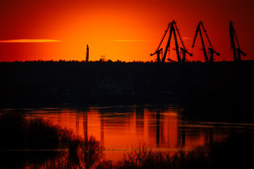 silhouettes of port cranes on the background of a beautiful order