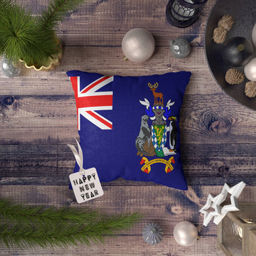 Happy New Year tag with South Georgia and the South Sandwich Islands flag on pillow. Christmas decoration concept on wooden table with lovely objects.