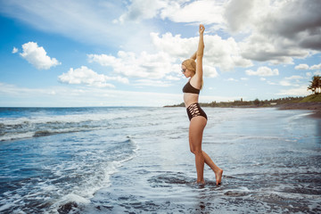 Fototapeta na wymiar sexy girl in a swimsuit walks the black beach