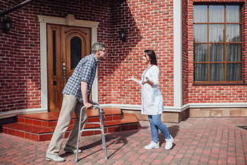 Nurse talking to elderly man in wheelchair in a nursing home ! Nice day!