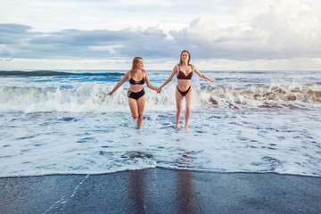 Two girls running from the waves