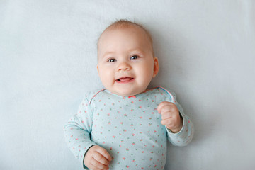 Portrait of a smiling baby in bed. Baby smiling and looking up to camera. Good morning!