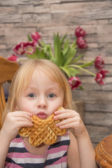 The child eats belgian waffles. child is having fun at breakfast