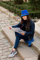 Fototapeta premium A young woman sits on the stairs in the old courtyard, and reads the map. Lviv, Ukraine