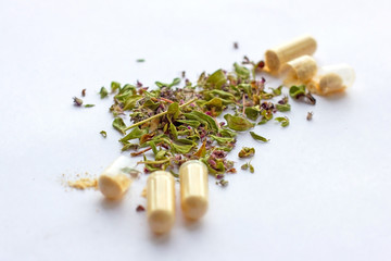 Nutritional supplements pills and capsules on dried herbs background. Alternative herbal medicine, naturopathy and homeopathy, medical pharmaceutical drugs, organic vitamins and multivitamins concept