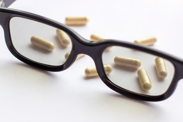Pills, capsules and tablets with glasses on light background. Pharmacy and medicine concept....