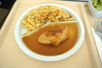 Chicken breast served with noodles and gravy on a tray