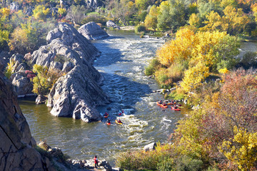 View from the mountain on rowers kayakers in whitewater river on a sunny autumn day