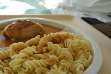 Chicken breast served with noodles and gravy on a tray
