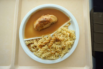 Chicken breast served with noodles and gravy on a tray