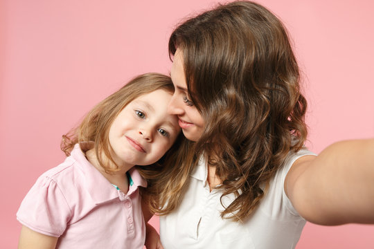 Close up selfie shot woman in light clothes have fun with cute child baby girl. Mother, little kid daughter isolated on pastel pink wall background, studio portrait. Mother's Day, love family concept.