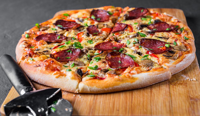 Pepperoni Pizza with Mozzarella cheese, salami, pepper, Spices and mushrooms. Italian pizza on Dark grey black slate background
