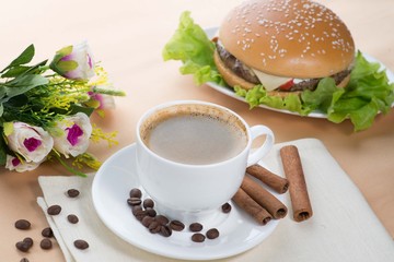cup of coffee and burger on a served white table