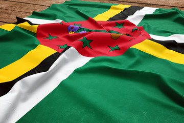 Flag of Dominica on a wooden desk background. Silk Dominican flag top view.