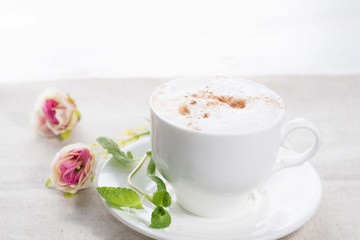 white cup of coffee on a background of scattered flower buds on a white background