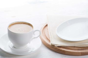 cup of coffee and an empty plate next to the served white table