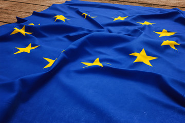 Flag of European Union on a wooden desk background. Silk EU flag top view.