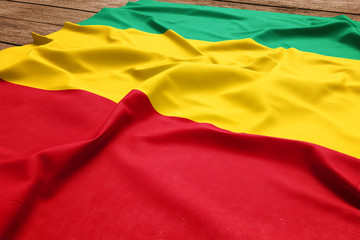 Flag of Guinea on a wooden desk background. Silk Guinean flag top view.