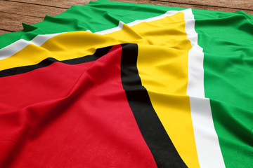 Flag of Guyana on a wooden desk background. Silk Guyanese flag top view.