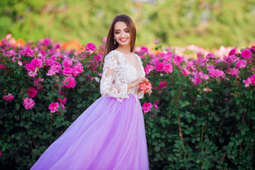 Obraz na płótnie Canvas Beautiful girl wearing elegant dress posing near colorful flowers. Art work of romantic woman .