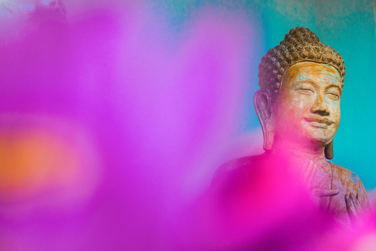 Stone carved statue of Buddha surrounded with colorful flowers