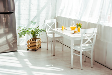 interior of white kitchen with breakfast on table and sunshine