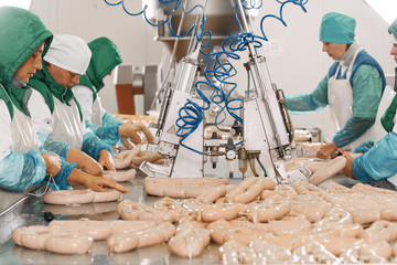 Women packing sausages at factory