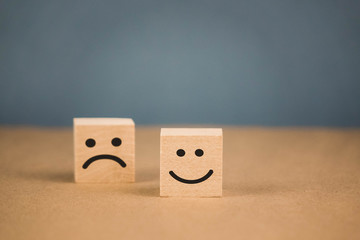 wooden cubes with smiling emoticons and sad one.