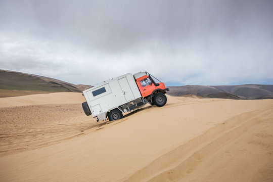 expedition vehicle climbing up a sand dune in mongolia