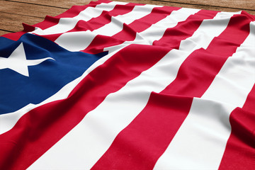Flag of Liberia on a wooden desk background. Silk Liberia flag top view.