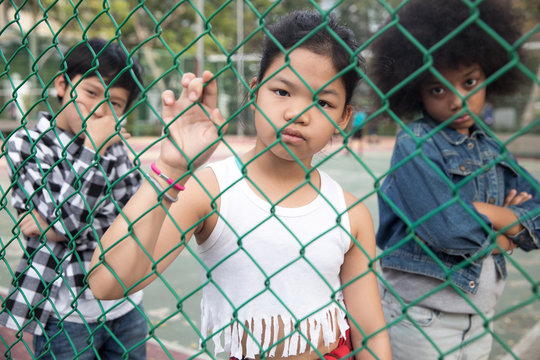 Cool girl looking thought the fence in a park