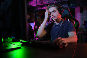 Professional young caucasian gamer playing online on his PC. He upset because of losing the game