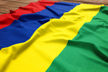 Fototapeta premium Flag of Mauritius on a wooden desk background. Silk Mauritian flag top view.