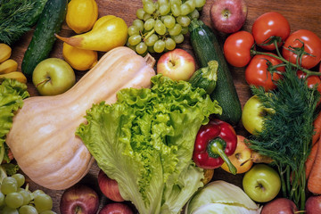 Various fresh vegetables and fruits on a wooden oak table.