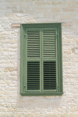 Window with wooden shutters in stone wall 