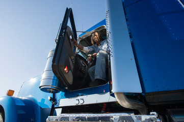 Portrait of a female truck driver in cab of truck.