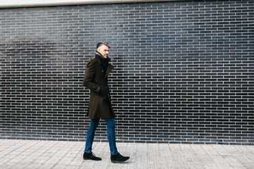 Trendy businessman walking down the street against black and white wall.