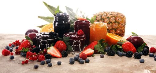 assortment of jams, seasonal berries, plums, mint and fruits in glass jar