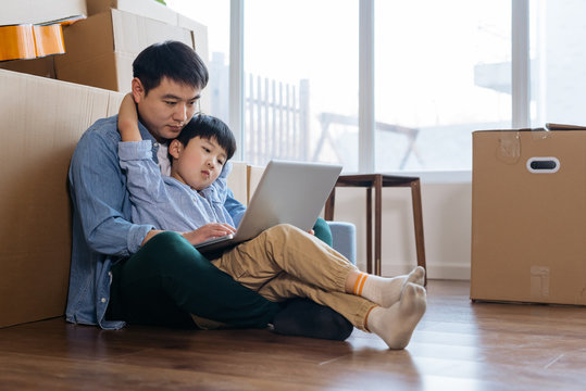 Father and son using computer in new house