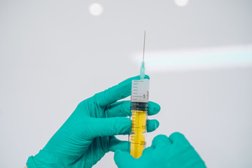 Hands in rubber gloves hold a disposable medical syringe with the drug