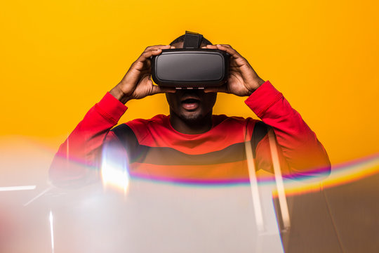 Black happy man using VR glasses over a yellow background