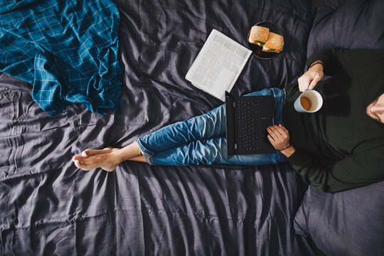 A Man Sitting on KIng-Size Bed and Using Laptop