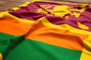 Flag of Sri Lanka on a wooden desk background. Silk Sri Lankan flag top view.